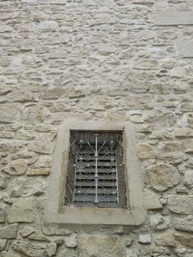 A small window with a bar in a stone wall Stock Photos