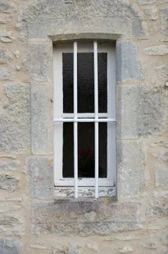 A small window with bars set in a stone wall Stock Photos