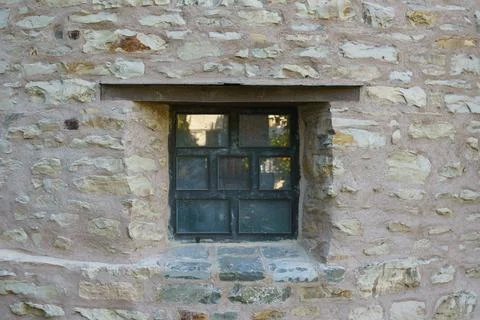 A small window in the thick stone wall of an old antique building. Stock Photos