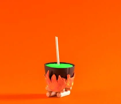 Small witch's pot with  potion is cooked on  fire on orange background. Hal.. Stock Photos