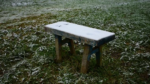 Small wooden bench on the grass, first snow Stock Footage 118907481