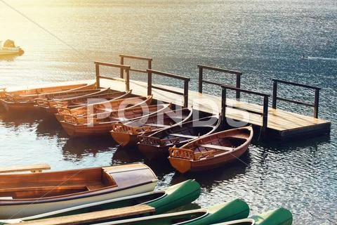 Small wooden boats and canoes tied to empty pier Stock Photos