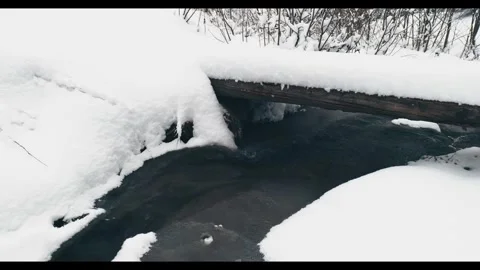 Small wooden bridge covered in deep snow over mountain stream in winter forest Stock Footage 328410161