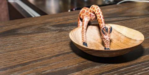 Small Wooden giraffe while drinking on a wooden plate Stock Photos