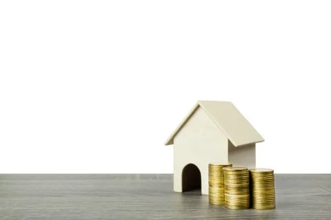 A small wooden house model with stack of golden coins on wood table isolated  Stock Photos