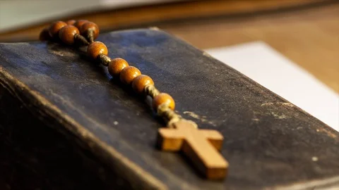 Small wooden rosary on an old dated prayer book rack to the cross focus macro Stock Footage 129427284
