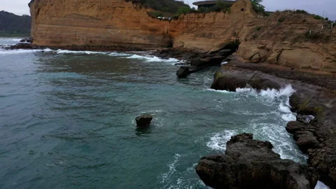 A small, worn out cape in which the waves are gently crashing on the rocks Stock Footage 234954630