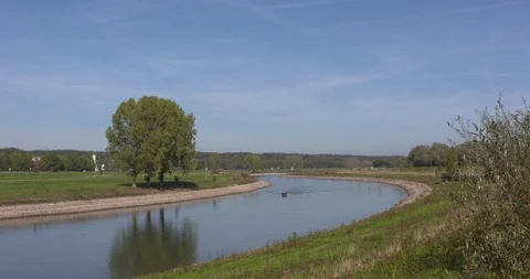 Small yacht sails upstream on the river leaving a wake pattern Stock Footage 96093479