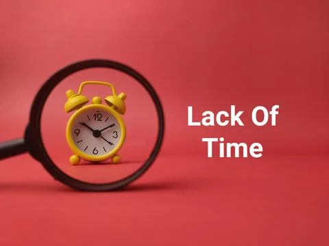 A small yellow alarm clock is captured through a magnifying glass on a red .. Stock Photos
