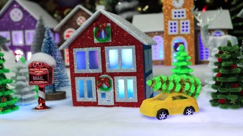 A small yellow car and a red house against the backdrop of a Christmas town Stock Footage 292768100