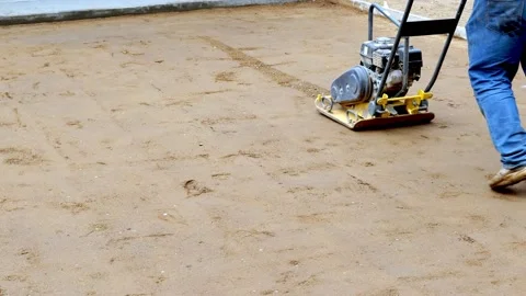 Small yellow compactor used on dirt before concrete is poured on driveway. Stock Footage 156760145