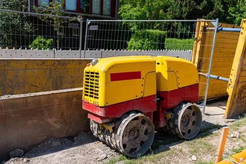 Small yellow construction roller for compacting soil at a construction site. Stock Photos