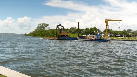 Small Yellow Excavator Operating on Floating Platform by a seawall. Compact exca Stock Footage 314809082
