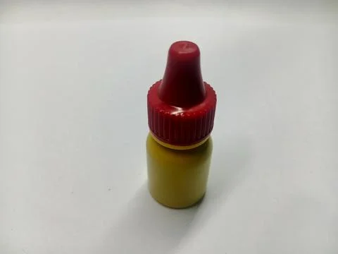 Small yellow plastic dropper bottle with red screw cap on white background Stock Photos