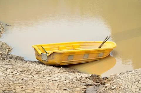 Small Yellow Plastic Rowboat on Cracked Dry Earth. Stock Photos