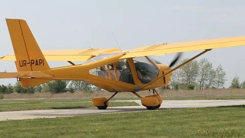 Small yellow private airplane with propeller in front is taxing on runway. Video stock 120870041
