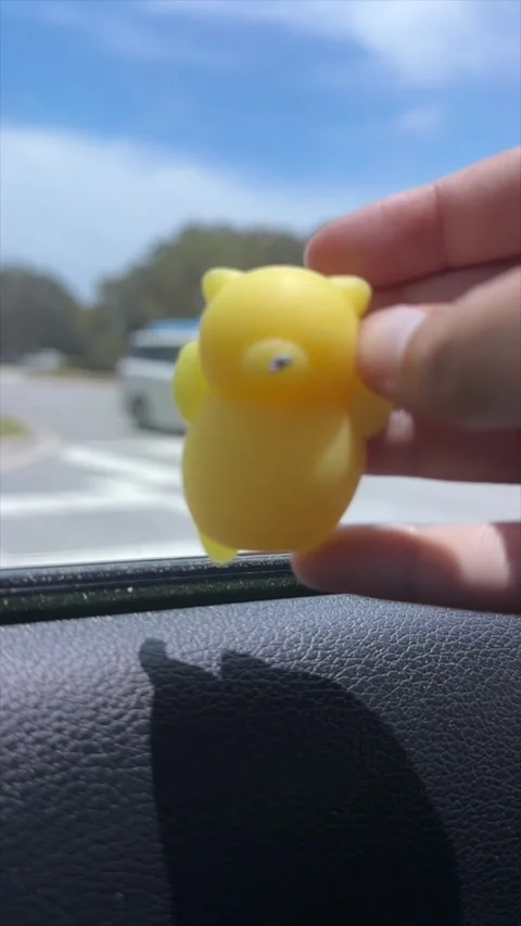 Small Yellow Toy Figure Held Against a Sunny Outdoor Background Stock Footage 337198456