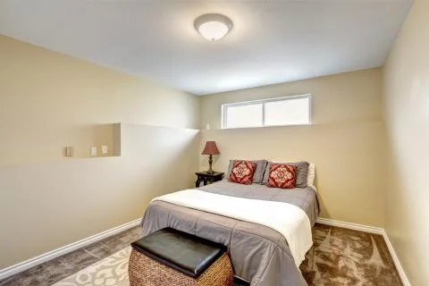 Small yet elegant bedroom in soft creamy tones with wicker chest and bed with Stock Photos