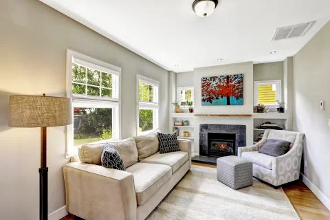 Small yet nice and cozy white living room with fireplace and comforatble beig Stock Photos