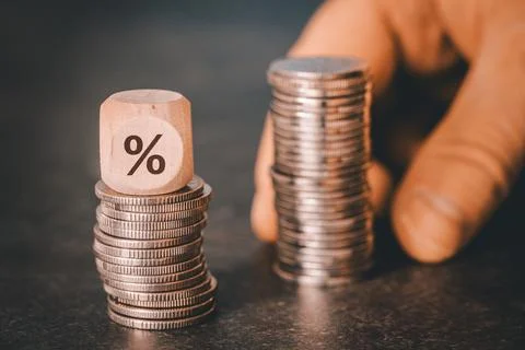 Smaller and larger stack of coins, Percent symbol on wooden cube  Stock Photos