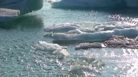 Smaller icebergs flow to left on wavy lake water Stock Footage 37899294