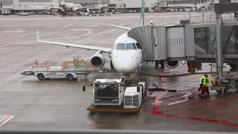 Smaller plane Parked At The Gate With workers walking around, Brussels airport Stock Footage 171870746