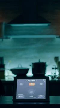Smart application on tablet placed on kitchen desk in empty house 库存照片