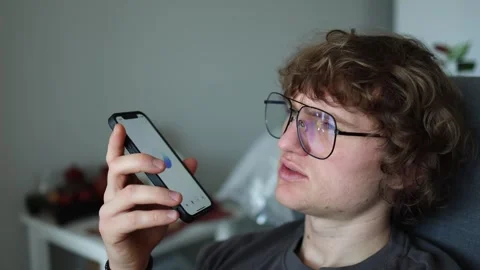 Smart assistant voice input young man holding phone close serious expression dig Stock Footage 305999781