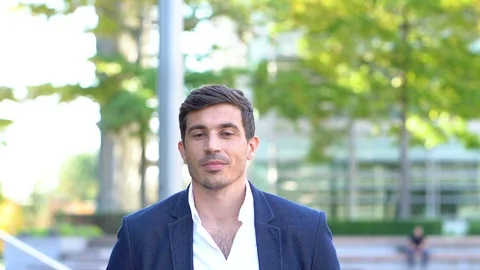 Smart attractive man looking at camera, in business park slow motion Stock Footage 96067266
