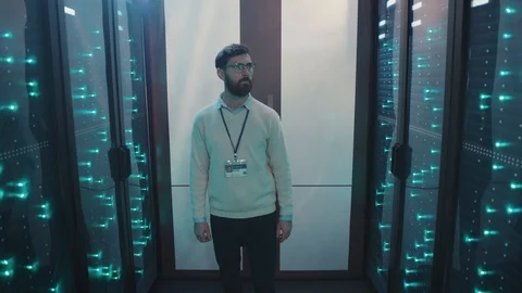 Smart bearded system administrator walking through network and data server rack Stock Footage 119231668