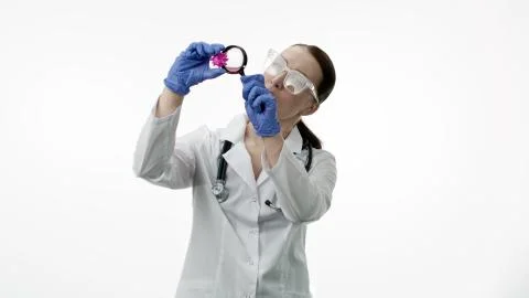 Smart beautiful lab assistant explores covid-19 virus cell with magnifying glass Stock Photos