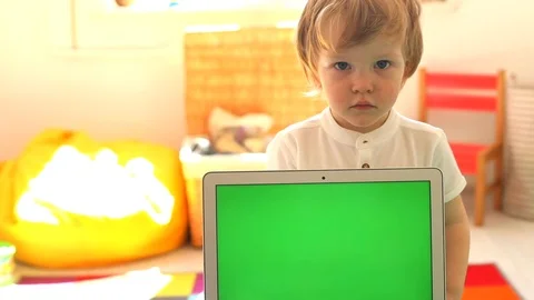 Smart blonde smiling boy in white shirt looking above the laptop green screen Video stock 109130674