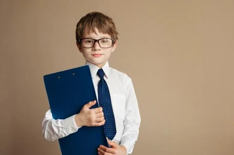 Smart boy in elegant suit and glasses sitting on a Chesterfield sofa with a Stock Photos