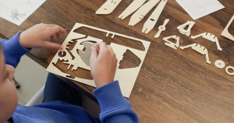 Smart boy hands draw out airplane plywood part of sheet over desk Stock Footage 323972545
