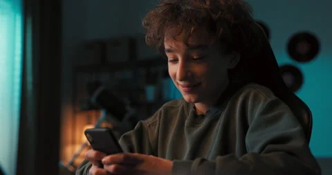 Smart boy is looking for answers to test on phone. He has remote lessons on 動画素材 200874733