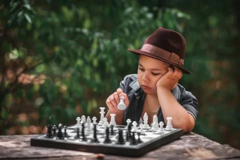 Smart boy playing chess in a green forest Stock Photos