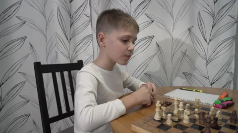 Smart boy is playing chess with his mother in the kitchen, sitting at the table Video stock 257589001