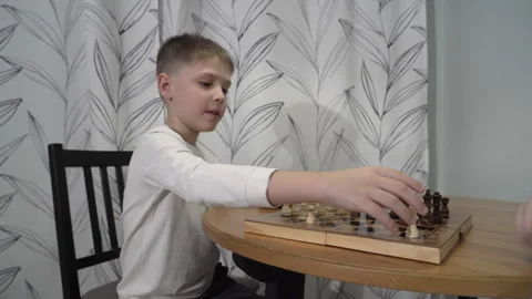 Smart boy is playing chess with his mother in the kitchen, sitting at the table Video stock 259309090