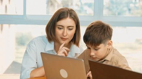 Smart boy playing laptop with multicultural friend learning prompt. Erudition. Foto stock