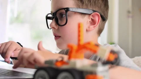 Smart boy programs robot car at laptop. Kid learning coding and programming. Stock Footage 196792864