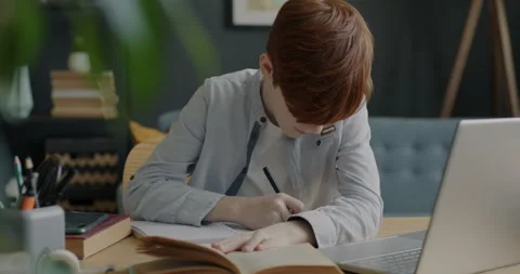 Smart boy reading textbook and writing i... | Stock Video | Pond5