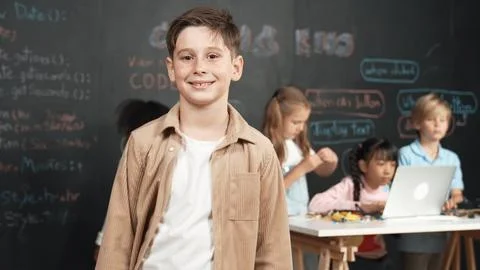 Smart boy smiling at camera while diverse friend working at board. Erudition. 스톡 사진