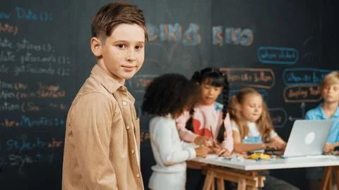 Smart boy smiling at camera while diverse friend working at board. Erudition. 스톡 사진
