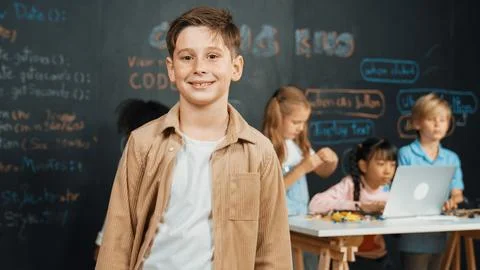 Smart boy smiling at camera while diverse friend working at board. Erudition. 스톡 사진