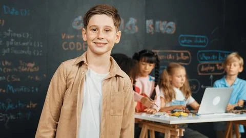 Smart boy smiling at camera while diverse friend working at board. Erudition. 스톡 사진