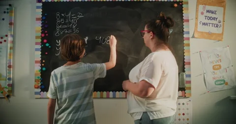 Smart Boy Solving Mathematical Problems on the Chalkboard. Female Teacher Stock Footage 313735612