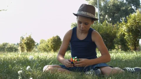 Smart Boy Solving A Rubik's Cube in the park.  Boy Tries To Finish Solving Stock Footage 116047810