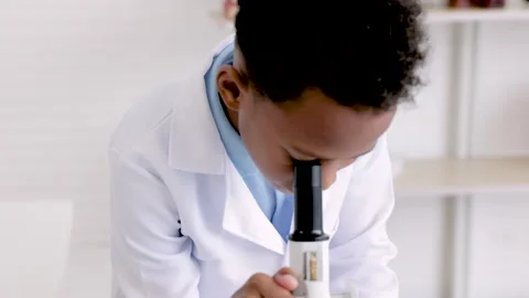 Smart boy student wearing lab coat using microscope equipment and tube anal.. Stock Footage 243656143