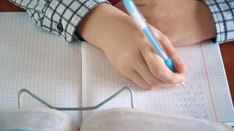 Smart boy writes numbers and doing mathematical calculation in notebook at Video stock 106276907