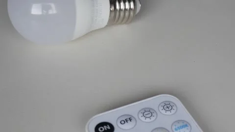 Smart Bulb and Remote Control Highlighting Modern Lighting Solutions Stock Footage 315162674